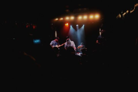 Algernon Cadwallader on stage at Thekla in Bristol, warm and blue stage lights above the band, silhouetted crowd in the foreground.