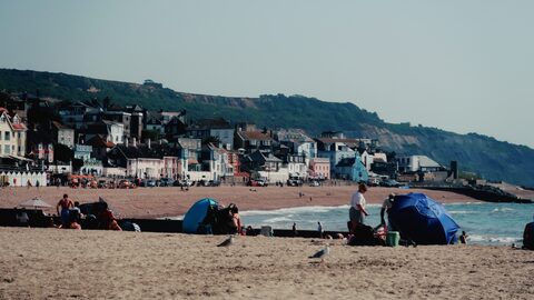 Sandy beach at Lyme Regis with colourful seafront houses and the Jurassic Coast cliffs in the distance.