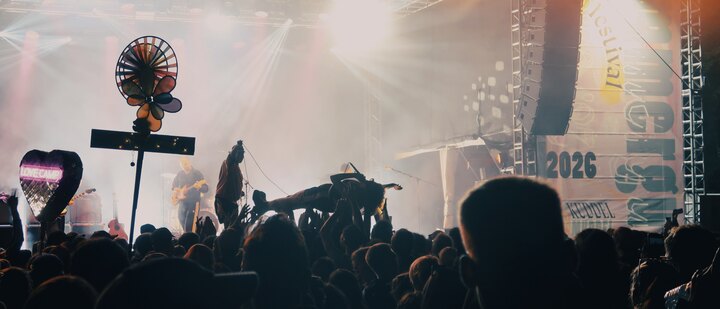 The singer of SPRINTS crowd-surfing on the raised hands of the audience during their performance at Immergut Festival 2026, with smoky stage lights and the festival banner behind.