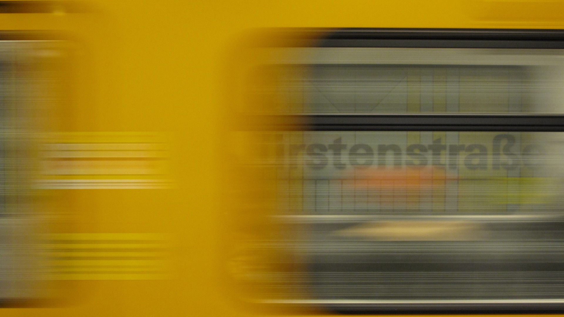 U‑Bahnhof Kurfürstenstraße platform sign seen through a train window as a yellow U‑Bahn blurs past. Photo taken in February 2024.